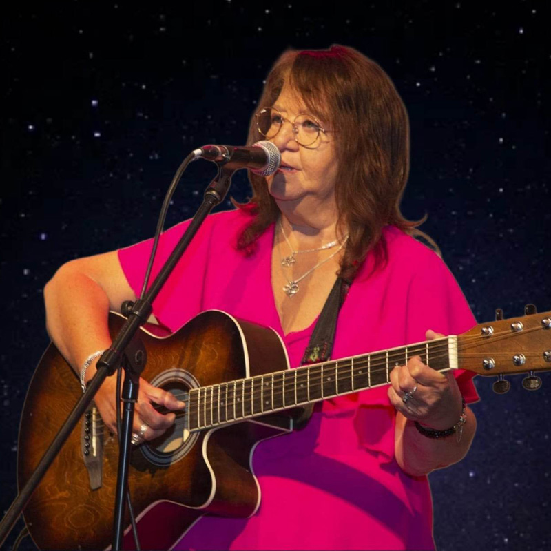 troubadour Renate Spierdijk met een akoetische gitaar bij een microfoon