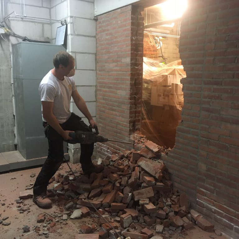 man breekt muur kapot