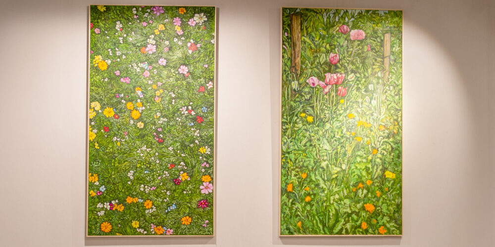 twee schilderijen met veld van groen en kleurrijke bloemen in de expositieruimte van Het Gele Huis