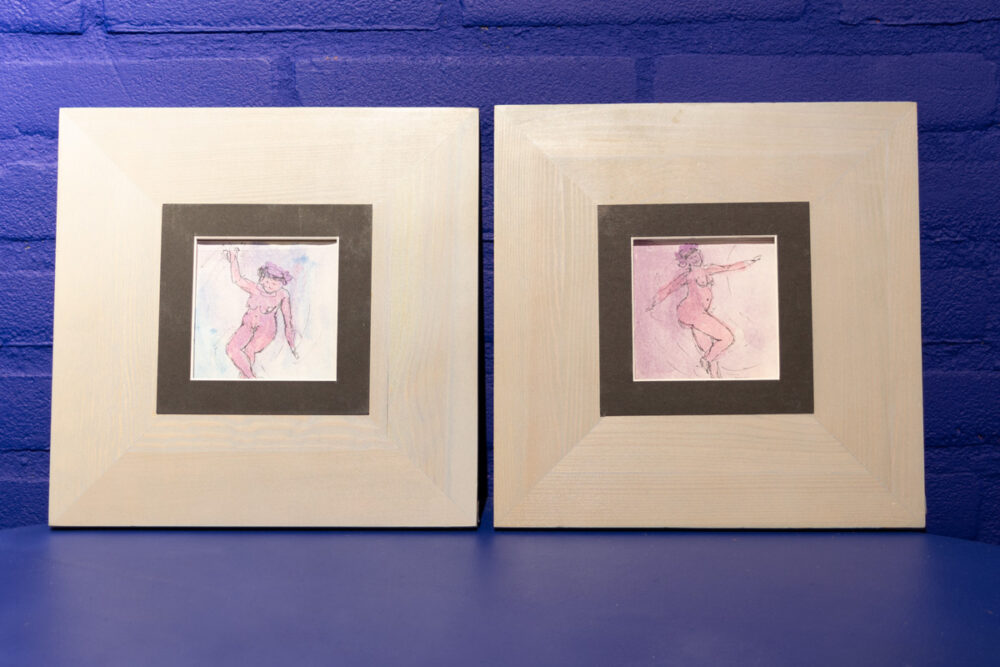 Twee houten lijstjes met elk een tekening van een naakte danseres