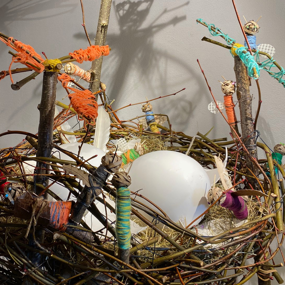 nest met een ei en met figuurtjes gemaakt van draad en takjes