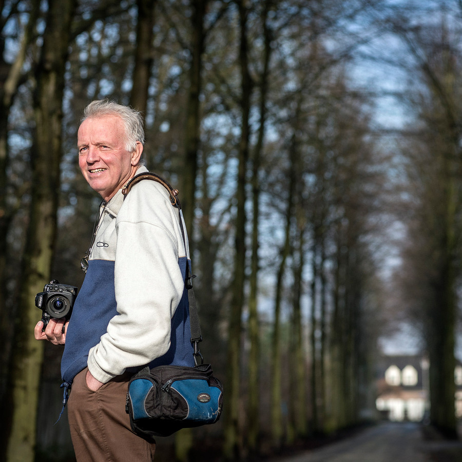 fotojournalist Piet den Blanken in een bos met een fotocamera in zijn hand