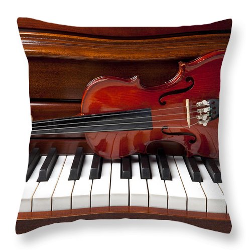 een kussen met een afdruk van een viool op de toetsen van een piano