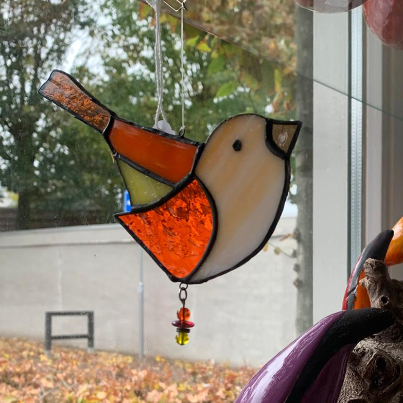 raamhanger met een vogel van glas-in-lood hangt voor een raam