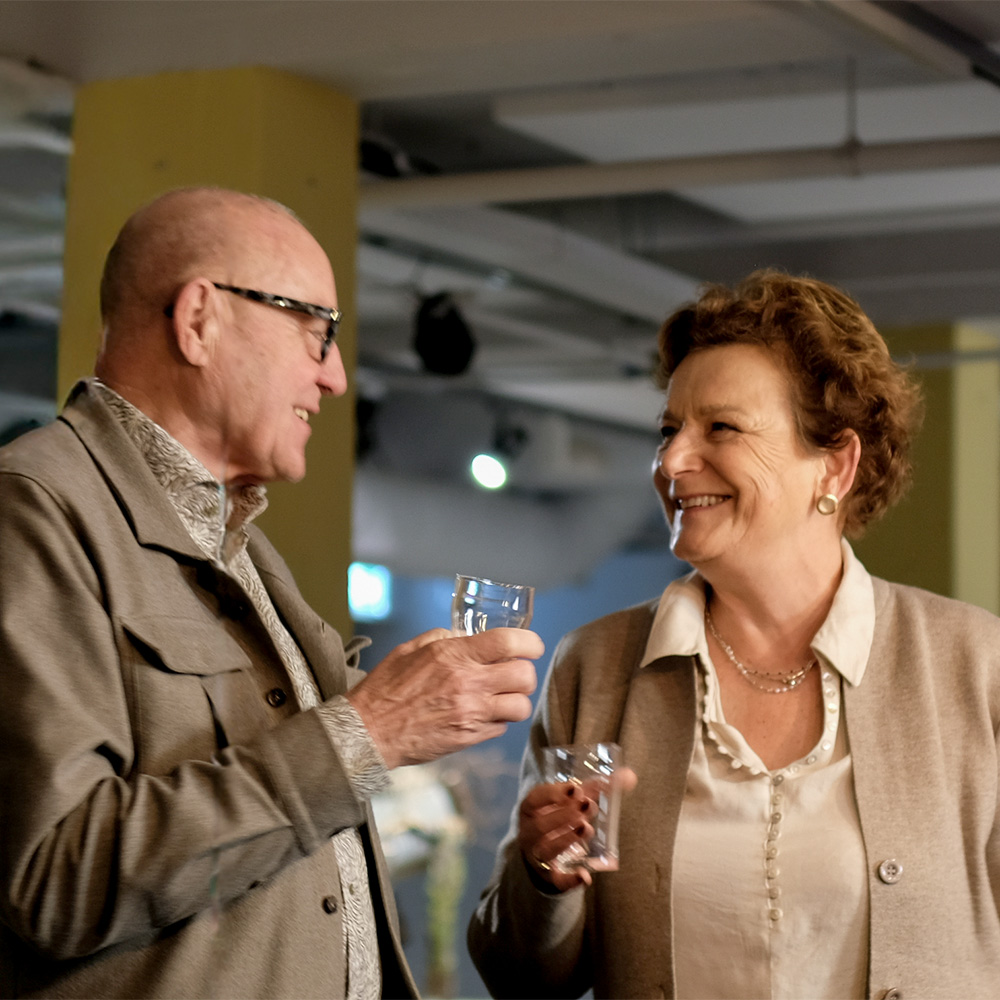 twee kunstliefhebbers praten met een glas in hun hand