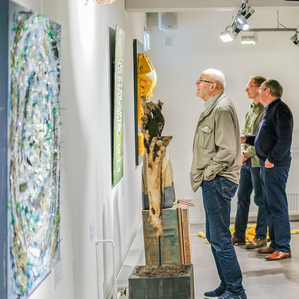 man bewondert een kunstwerk aan de muur tijdens een kunstexpositie