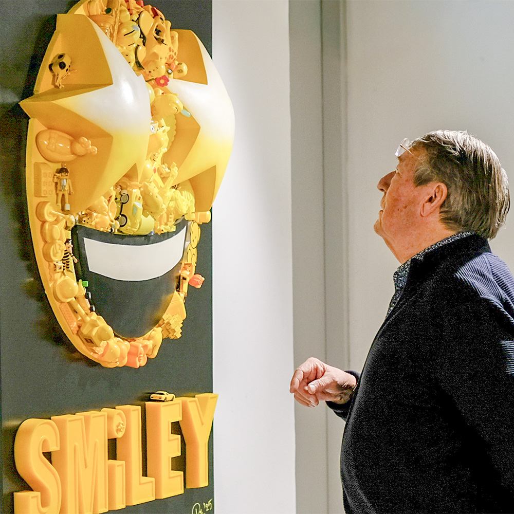 man bekijkt een kunstwerk met een smiley